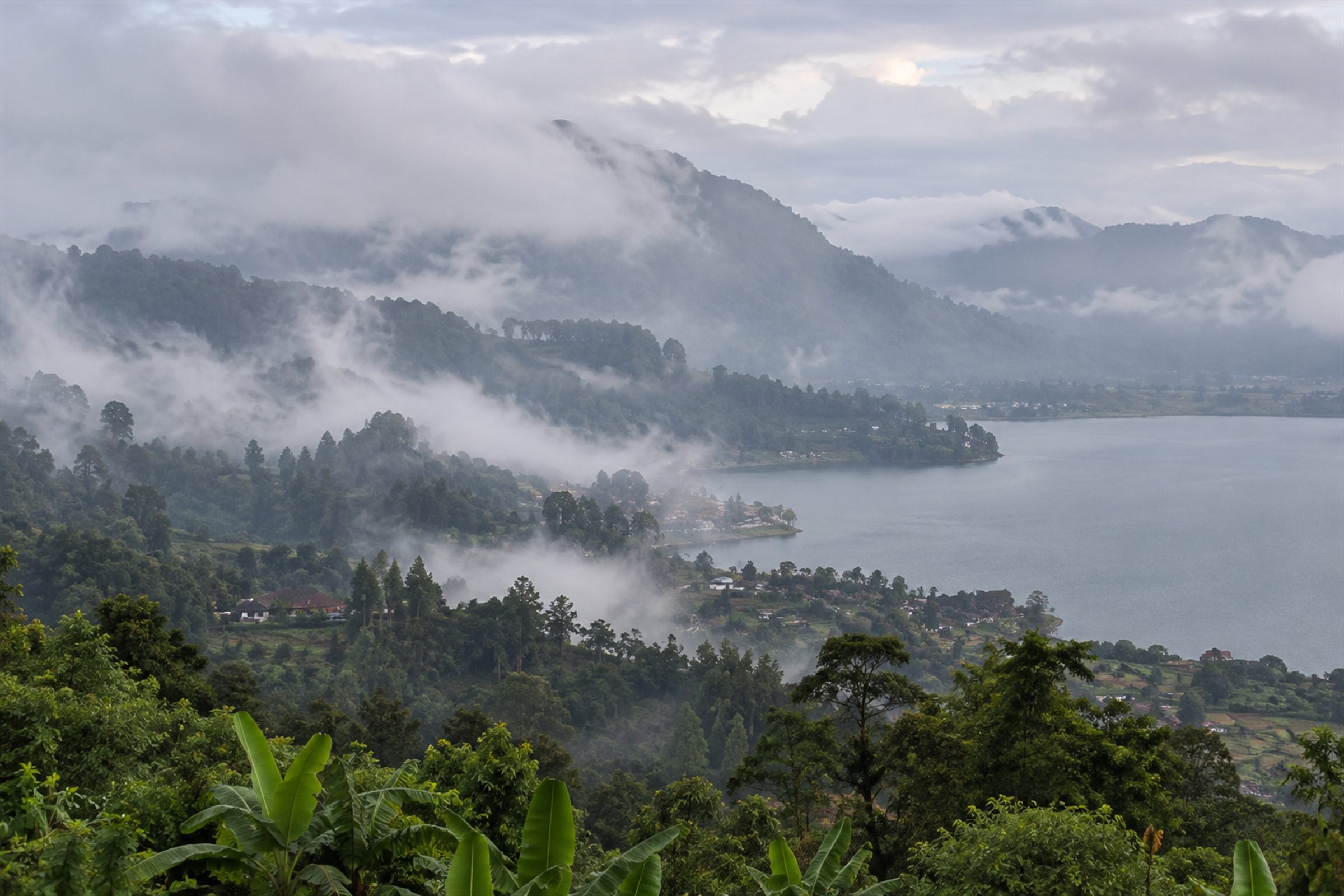 Mist rolling over forested hills and down to a lake in the Bedugul highlands