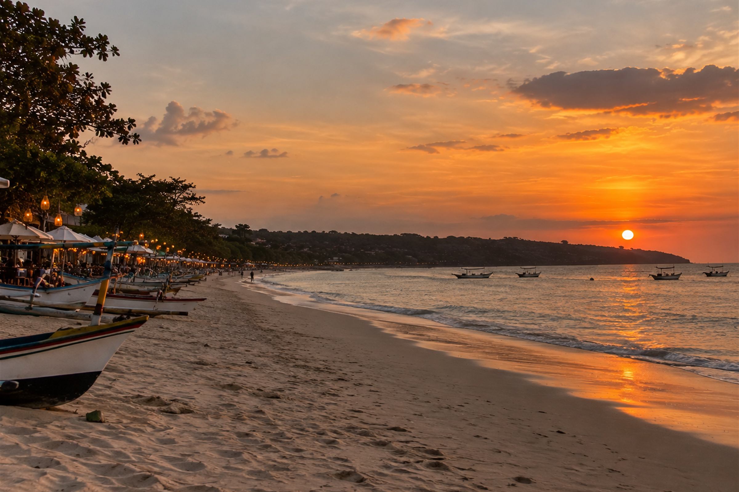 Outrigger boats drawn up on Jimbaran beach at sunset with the lamps of the seafood grills coming on